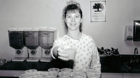 Woman handing out juice cups at Gloria's Place cafeteria c1988